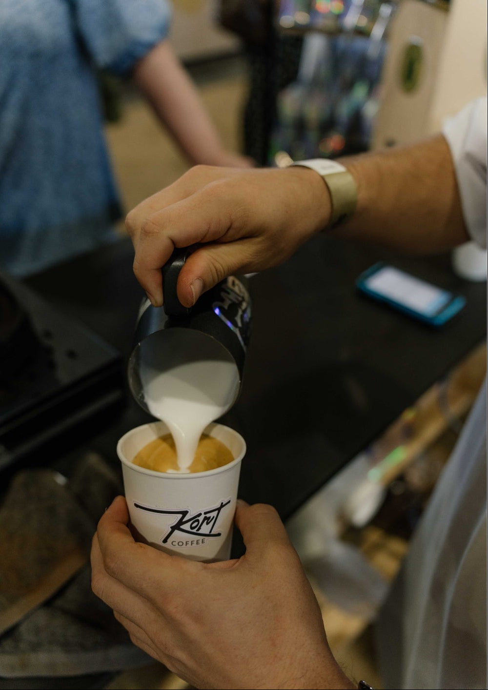 Barista pouring milk into a coffee cup with a blurred background